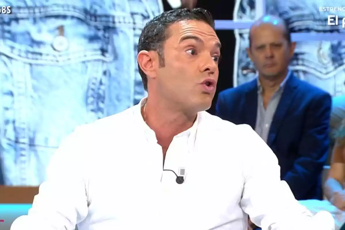 Antonio Rossi de cabello corto y camisa blanca hablando en un programa de televisión con fondo de chaqueta de mezclilla y personas sentadas detrás Antonio Rossi de cabello corto y camisa blanca hablando en un programa de televisión con fondo de chaqueta de mezclilla y personas sentadas detrás