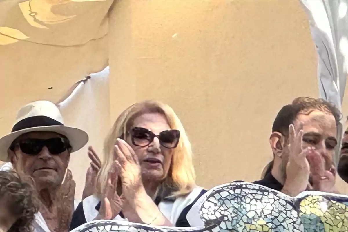 Amador Mohedano, Gloria Mohedano y David Flores Carrasco aplauden al aire libre, una de ellas lleva sombrero blanco y gafas oscuras, otra tiene el cabello rubio y usa gafas grandes, y la tercera persona está a la derecha con barba y cabello corto, todos están detrás de una estructura decorada con mosaicos. Amador Mohedano, Gloria Mohedano y David Flores Carrasco aplauden al aire libre, una de ellas lleva sombrero blanco y gafas oscuras, otra tiene el cabello rubio y usa gafas grandes, y la tercera persona está a la derecha con barba y cabello corto, todos están detrás de una estructura decorada con mosaicos.