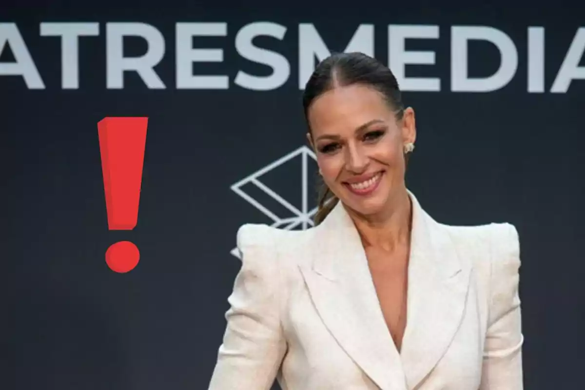 Eva González sonriente con saco blanco posando frente a un fondo oscuro con letras y un gran signo de exclamación rojo a su lado