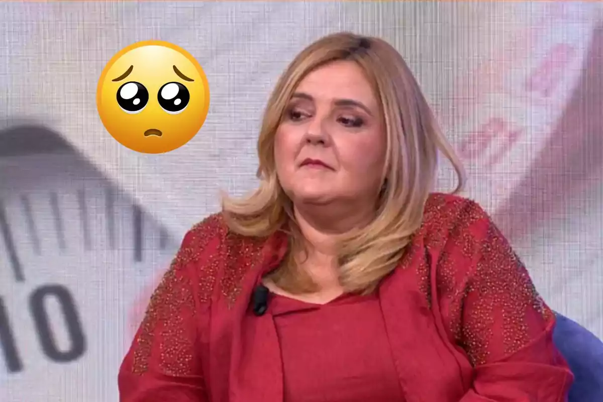 Dona de cabells rossos i expressió seriosa asseguda en un plató de televisió amb un emoji de carona trista al seu costat i una bàscula desenfocada al fons