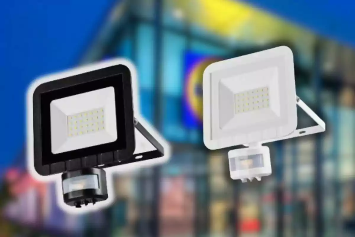Dos reflectores LED, uno negro y uno blanco, con sensor de movimiento al frente de un edificio moderno desenfocado Dos reflectores LED, uno negro y uno blanco, con sensor de movimiento al frente de un edificio moderno desenfocado