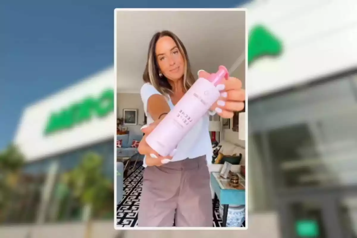 Mujer joven sostiene un envase rosa de producto cosmético frente a la cámara en una sala decorada con muebles y cuadros Mujer joven sostiene un envase rosa de producto cosmético frente a la cámara en una sala decorada con muebles y cuadros