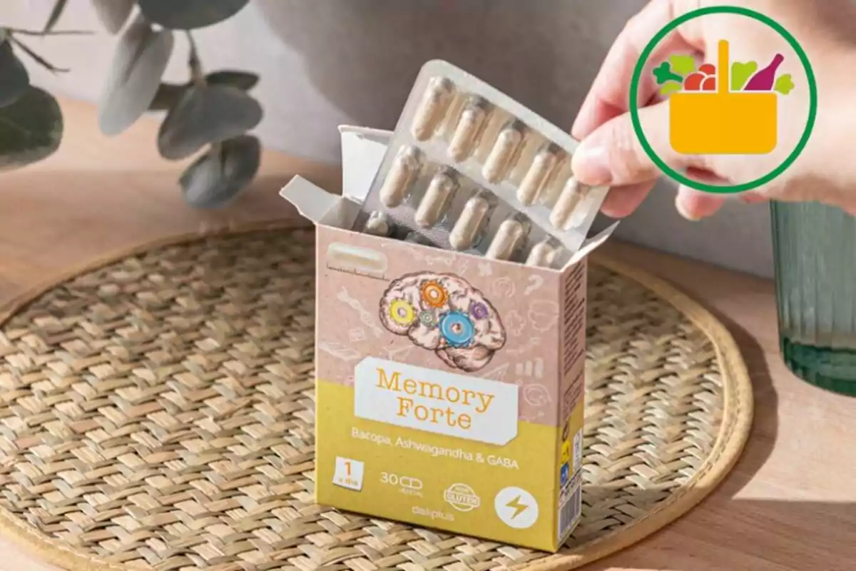 Persona sacando un blíster de cápsulas de una caja de suplemento Memory Forte sobre una mesa de mimbre Persona sacando un blíster de cápsulas de una caja de suplemento Memory Forte sobre una mesa de mimbre