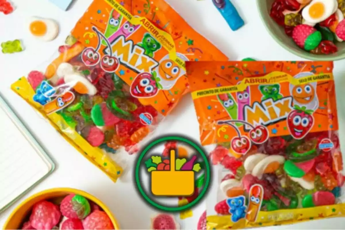 Bolsas de gomitas de colores con empaque naranja y dibujos de frutas sonrientes rodeadas de dulces y un ícono de canasta de supermercado al centro Bolsas de gomitas de colores con empaque naranja y dibujos de frutas sonrientes rodeadas de dulces y un ícono de canasta de supermercado al centro