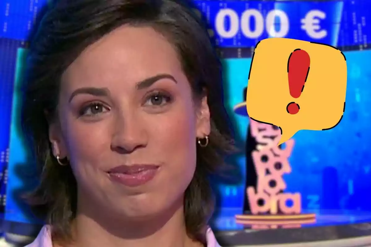 Rosa Rodríguez amb expressió somrient en un plató de televisió amb fons blau i una bafarada groga amb un signe d’exclamació vermell.