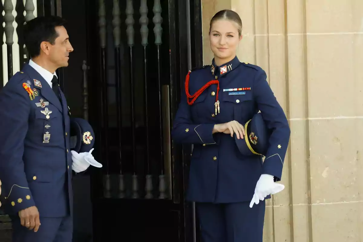 La princesa Leonor con uniforme militar azul posan en la entrada de un edificio de piedra, una de ellas sostiene una gorra y lleva guantes blancos La princesa Leonor con uniforme militar azul posan en la entrada de un edificio de piedra, una de ellas sostiene una gorra y lleva guantes blancos