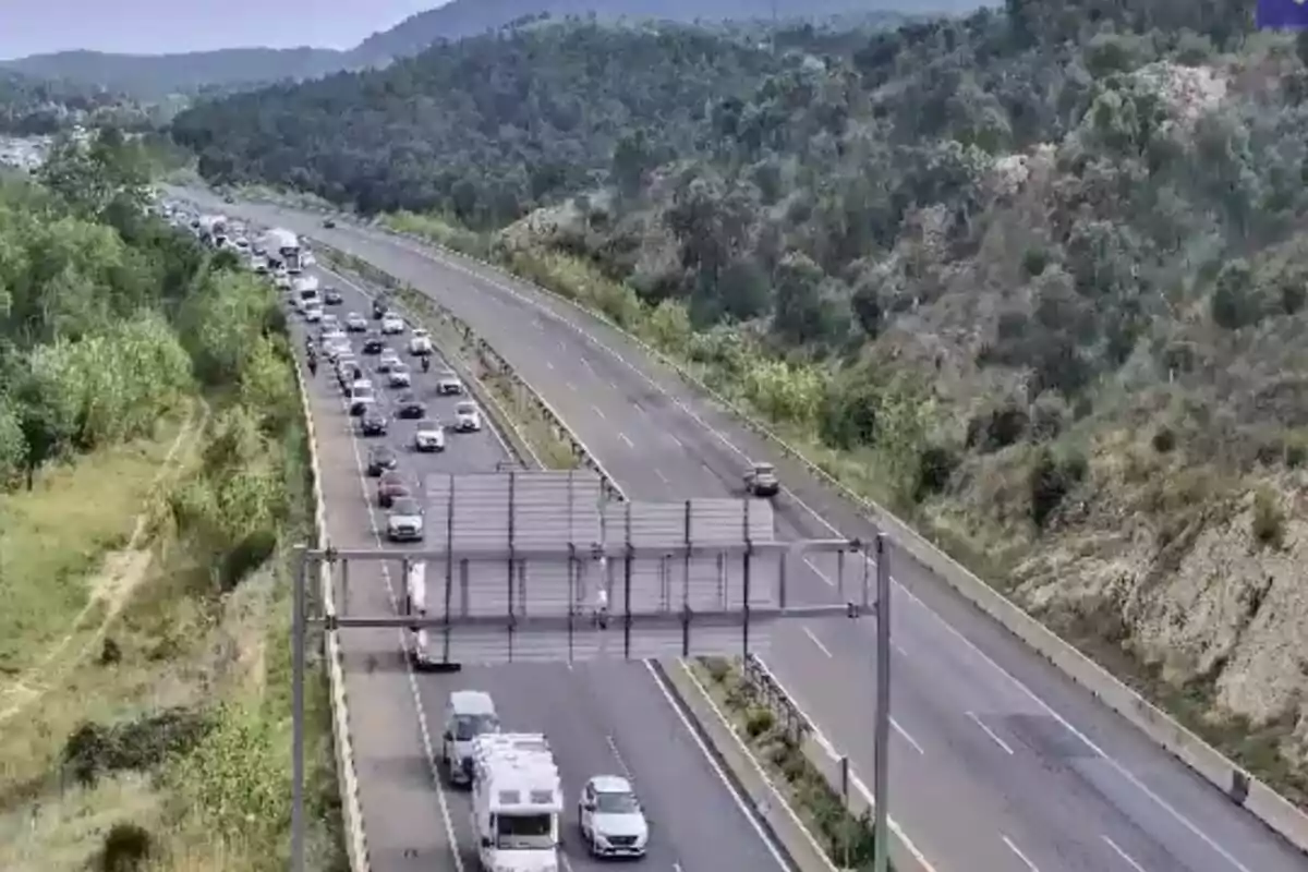 Carretera de varios carriles rodeada de vegetación con tráfico denso en un sentido y el otro sentido casi vacío