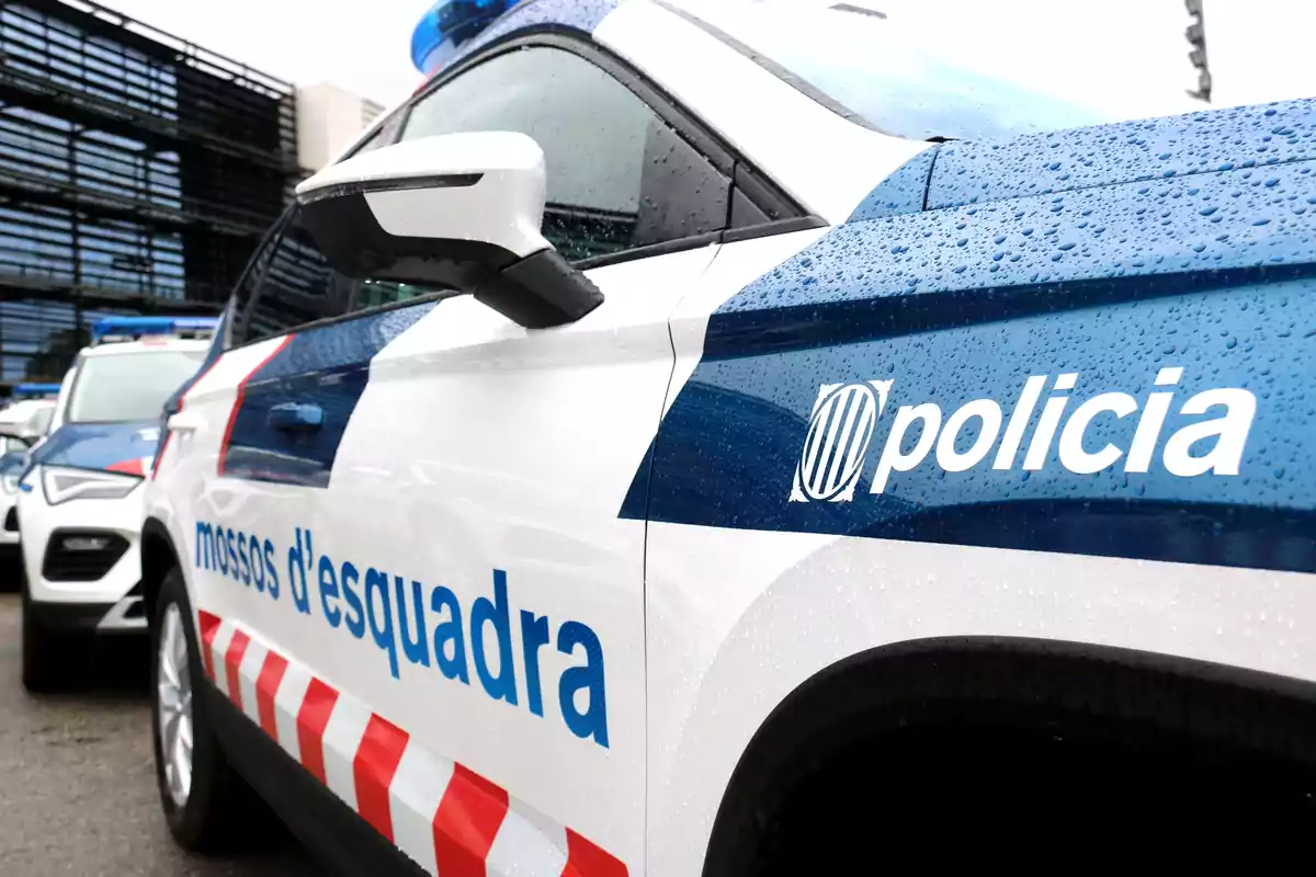 Vehicle dels Mossos d'Esquadra estacionat al carrer en un dia plujós.