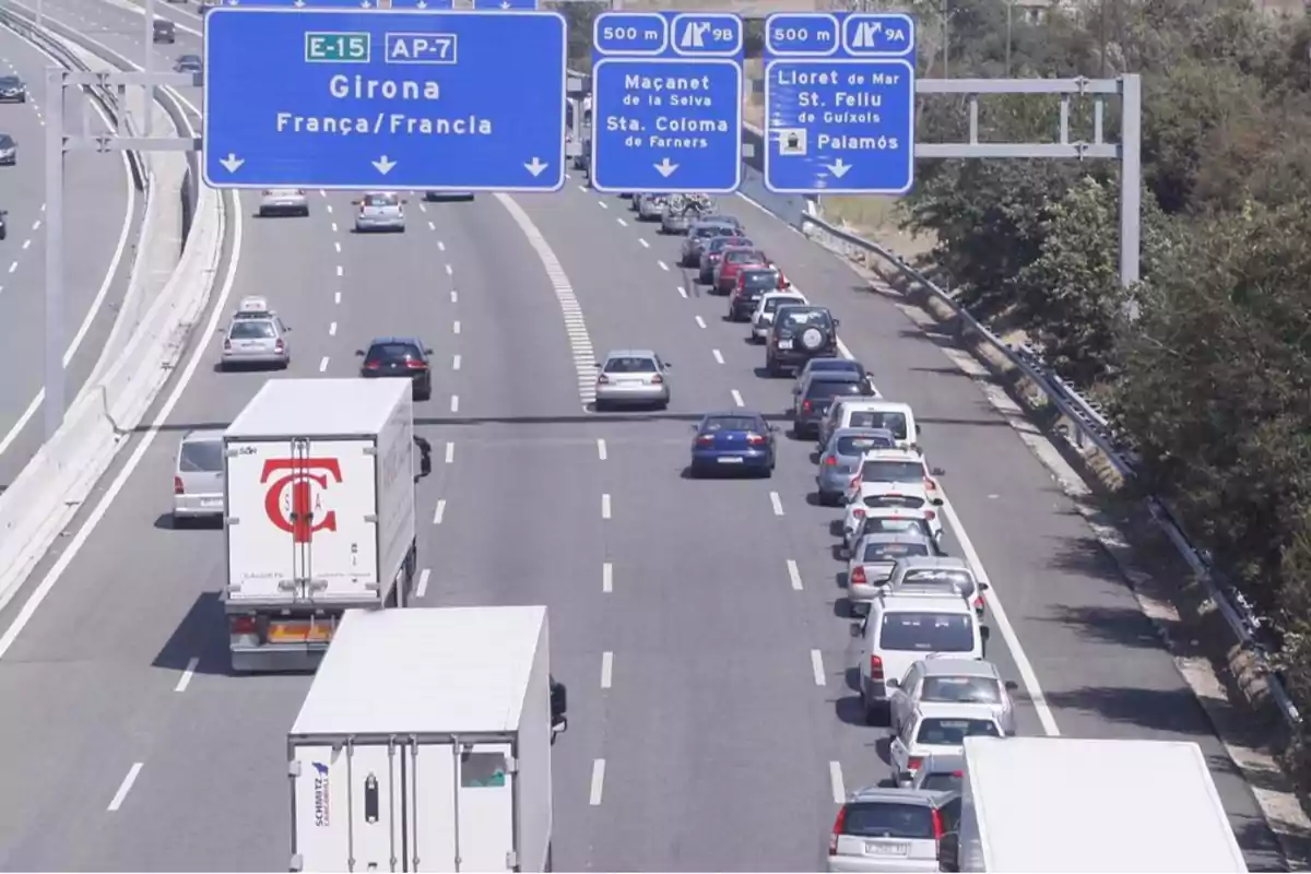 Una carretera con tráfico denso en un carril y señales de tráfico indicando direcciones hacia Girona, Francia, Maçanet de la Selva, Santa Coloma de Farners, Lloret de Mar, Sant Feliu de Guíxols y Palamós.