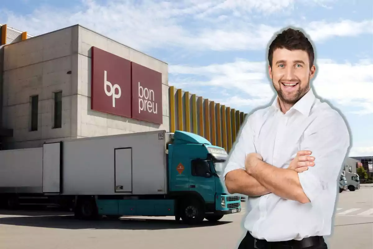 Un home somrient amb camisa blanca està dret davant un edifici de Bon Preu i un camió estacionat.