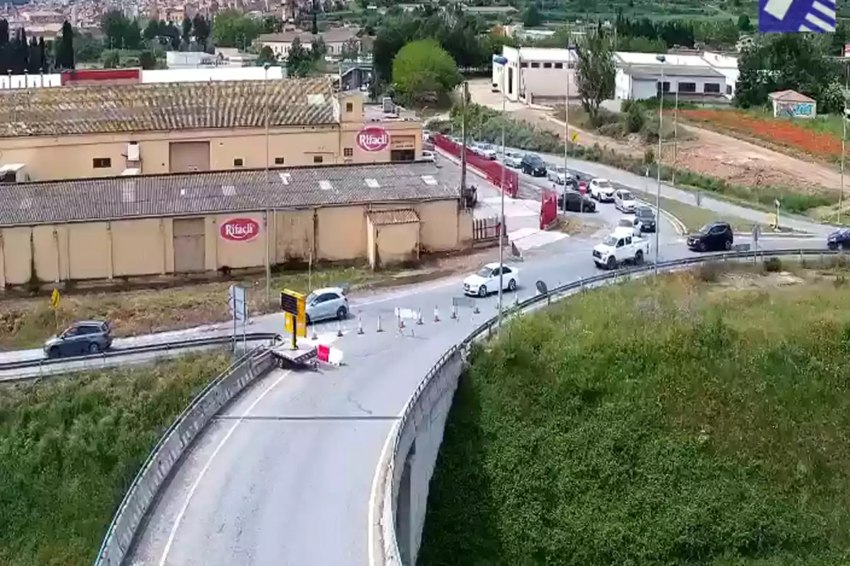 Una carretera con tráfico y un desvío cerca de un edificio industrial en un entorno semiurbano. Una carretera con tráfico y un desvío cerca de un edificio industrial en un entorno semiurbano.