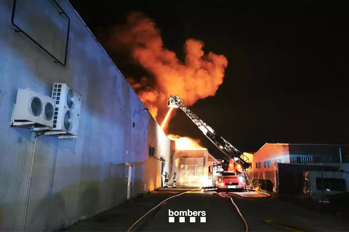 Bombers combatent un incendi en un edifici industrial durant la nit.