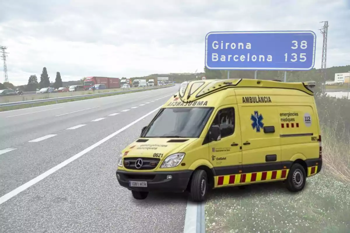 Una ambulància groga està estacionada al costat d´una carretera amb un cartell blau que indica les distàncies a Girona i Barcelona.