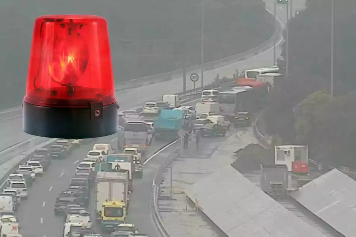 Una carretera congestionada amb diversos vehicles aturats i una llum d'emergència vermella superposada a la cantonada superior esquerra.