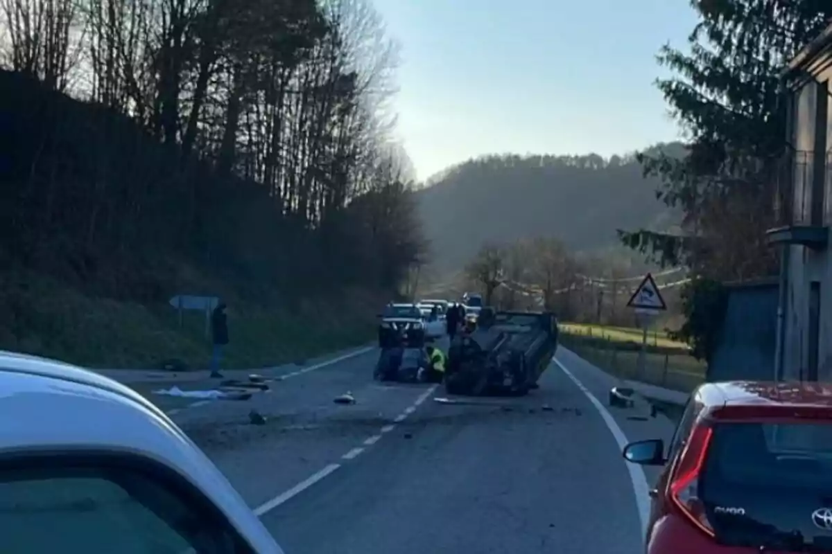 Un accident de trànsit en una carretera amb un cotxe bolcat i diversos vehicles al voltant.