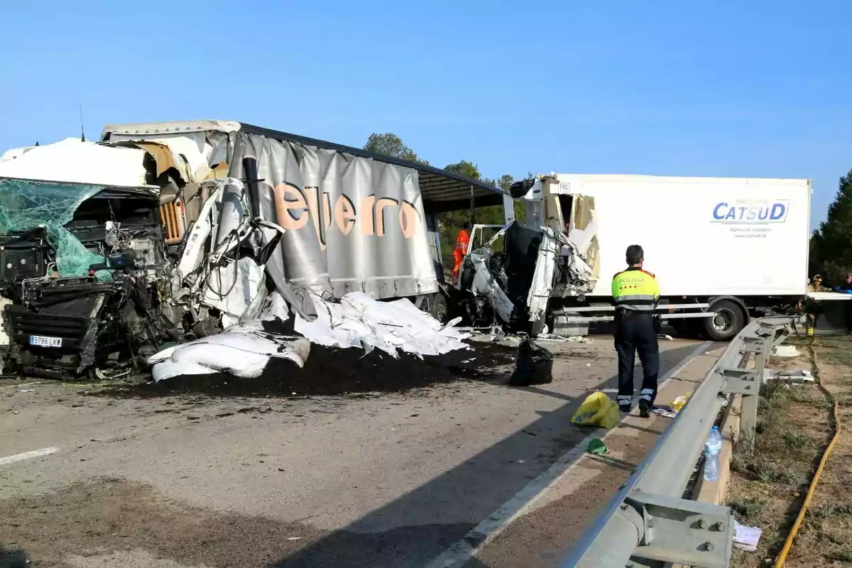 Accidente de tráfico entre dos camiones en una carretera, con un agente de policía observando la escena.