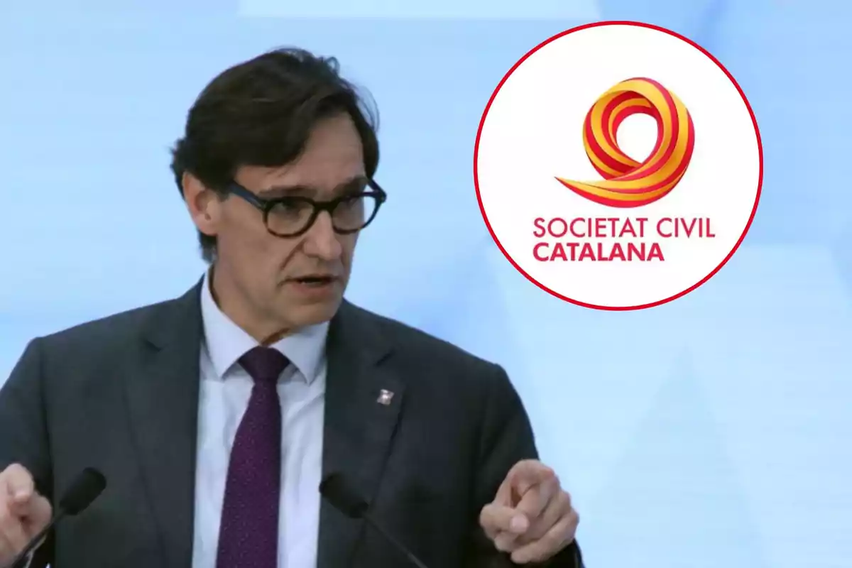 Home amb ulleres i vestit parlant en un micròfon amb el logotip de Societat Civil Catalana al fons.