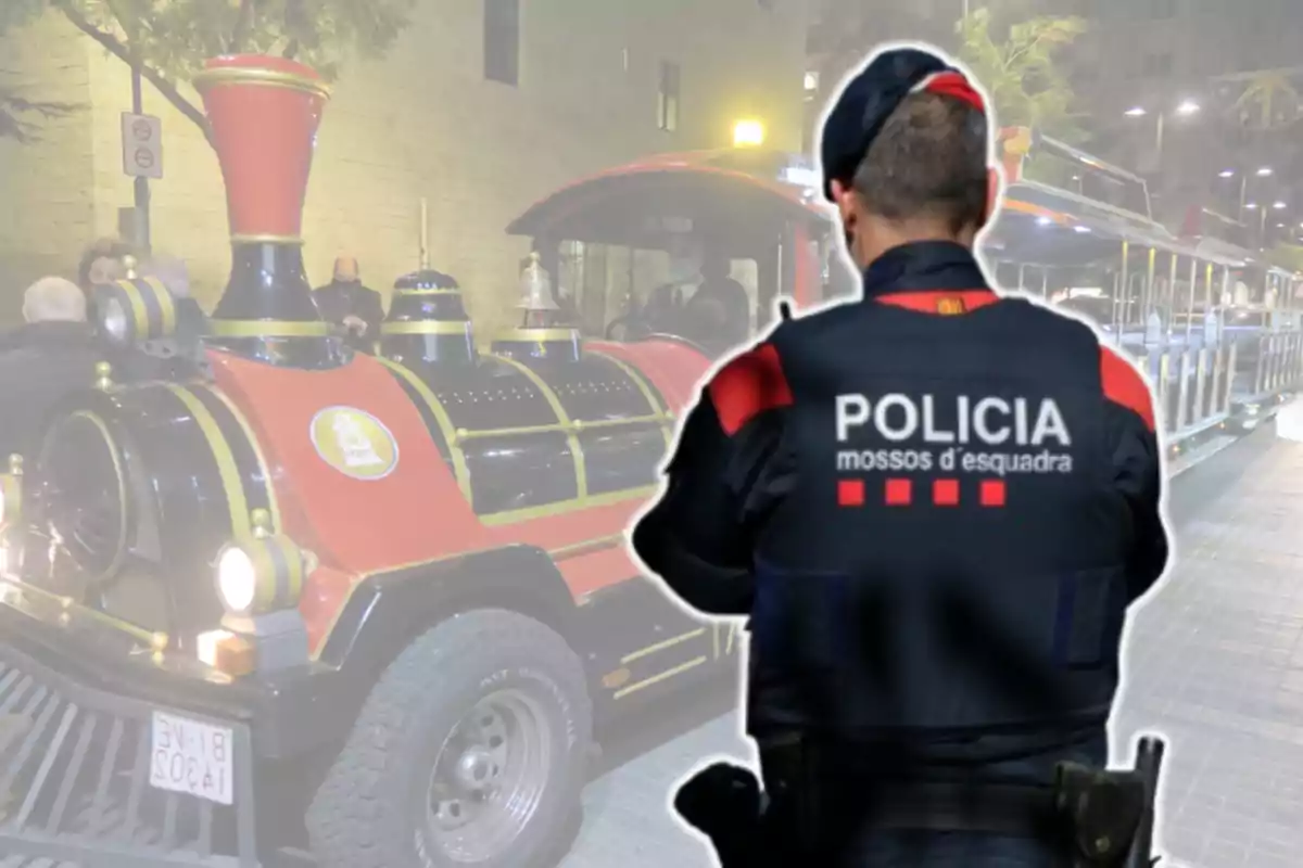 Un agente de policía de espaldas con uniforme de los Mossos d'Esquadra frente a un trende Navidad