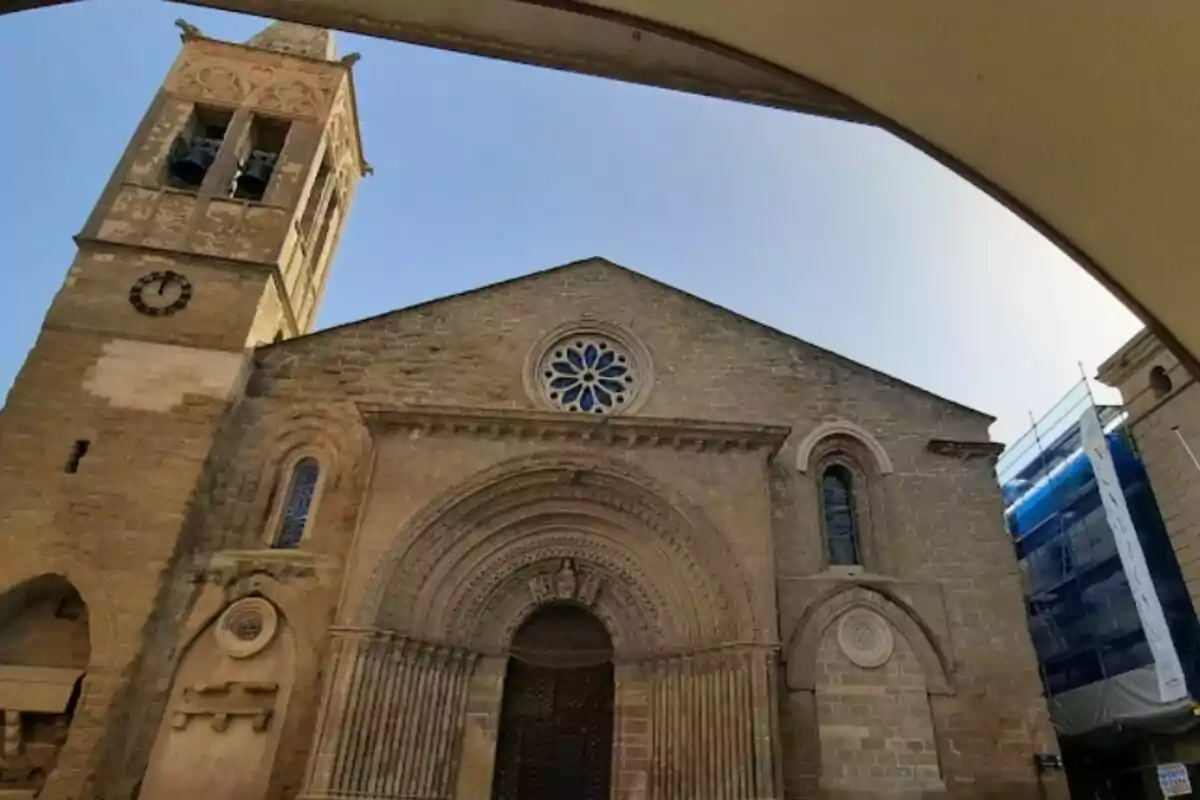 Façana d'una església de pedra amb un campanar i un rellotge, amb un cel clar de fons.