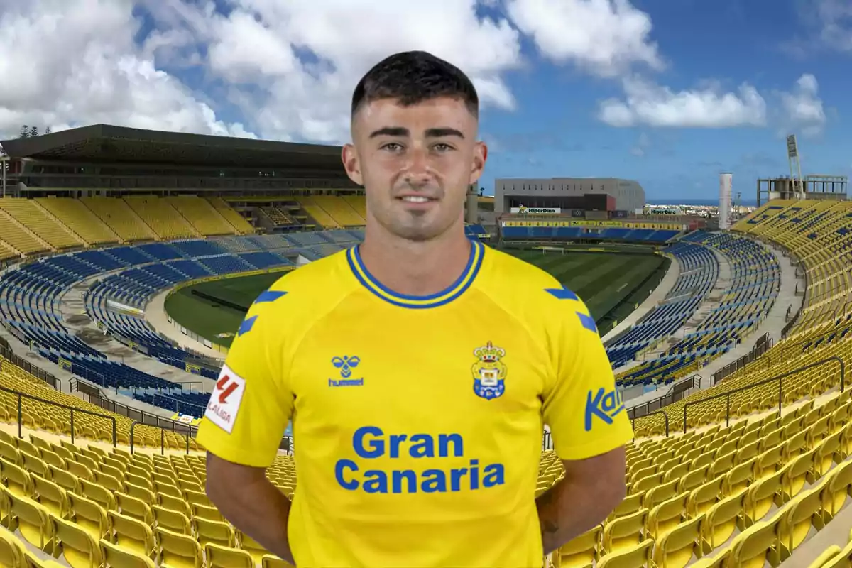 Un jugador de futbol amb la samarreta groga de l?equip de la UD Las Palmas posant en un estadi buit.