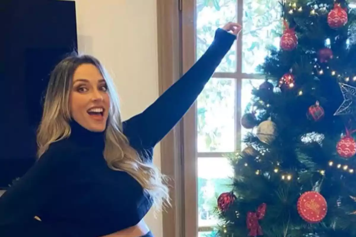 Mujer sonriendo junto a un árbol de Navidad decorado.