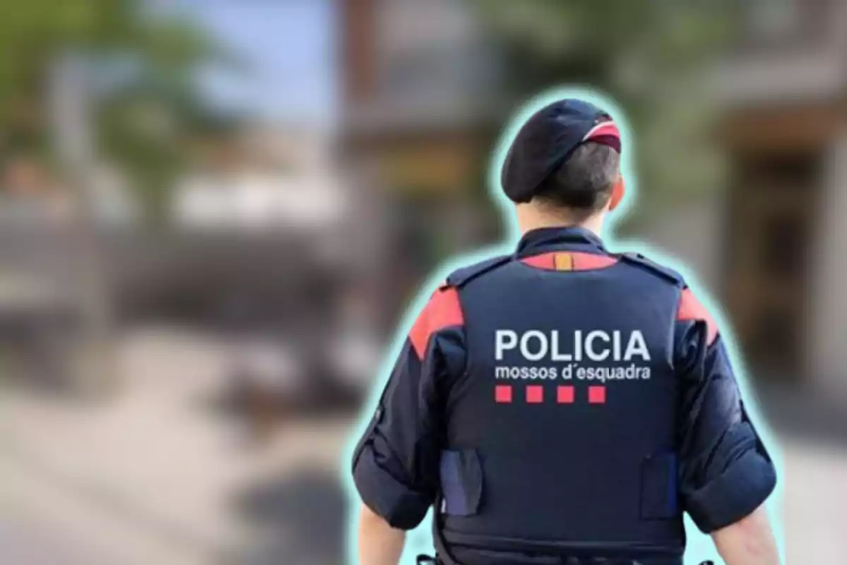 Policia dels Mossos d'Esquadra d'esquena amb uniforme i boina en un carrer desenfocat.