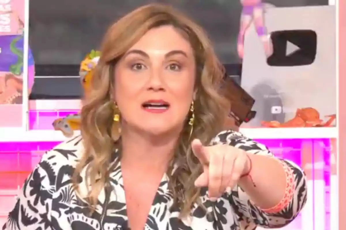 Carlota Corredera con cabello ondulado y rubio señala hacia adelante en un entorno colorido con un botón de reproducción de YouTube en el fondo en 'Tentáculos'. Carlota Corredera con cabello ondulado y rubio señala hacia adelante en un entorno colorido con un botón de reproducción de YouTube en el fondo en 'Tentáculos'.