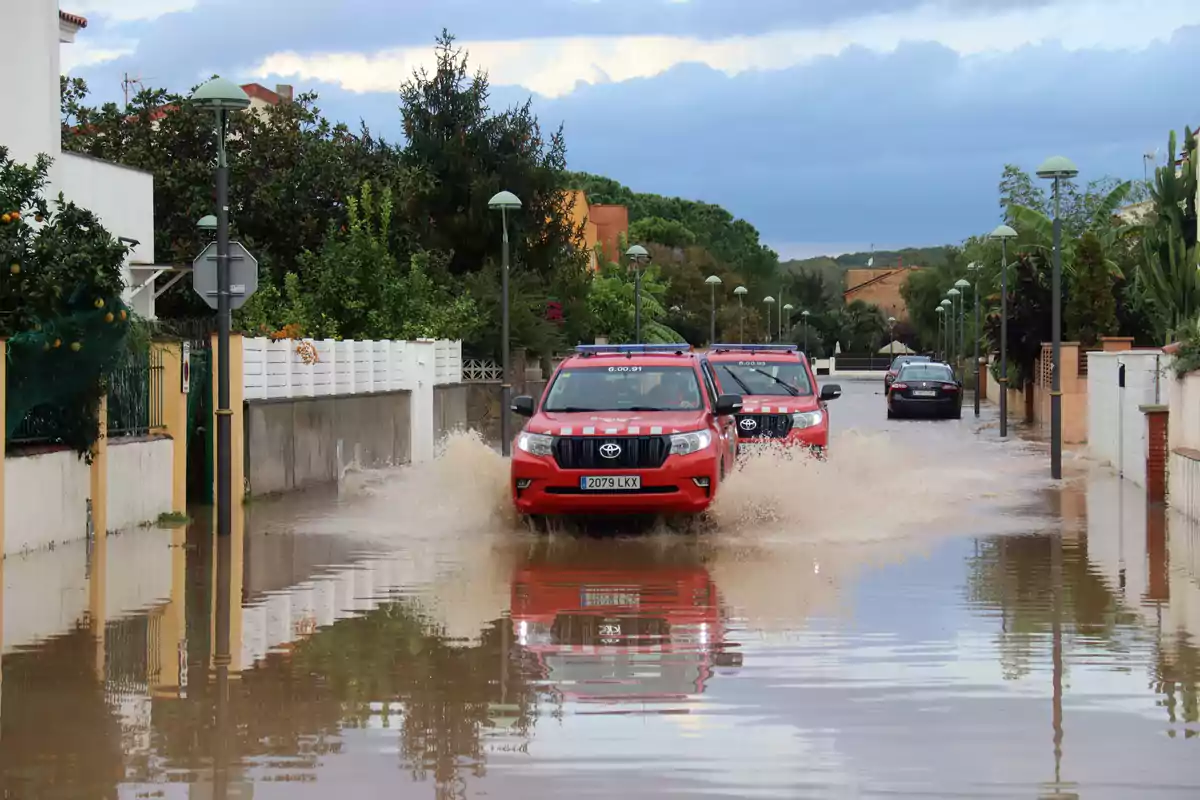 Vehículos de emergencia avanzan por una calle inundada tras fuertes lluvias.