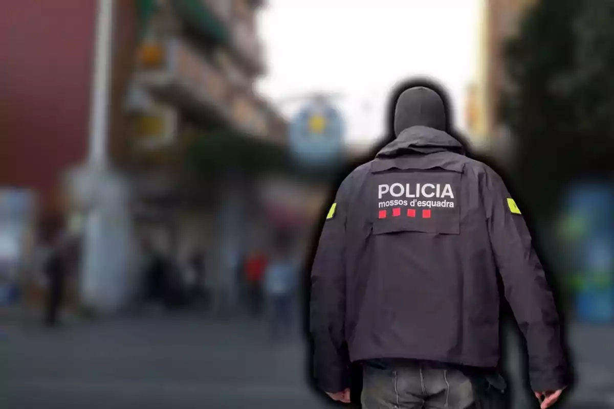 Un agent de policia d'esquena amb una jaqueta que diu Policia Mossos d'Esquadra en un carrer urbà.