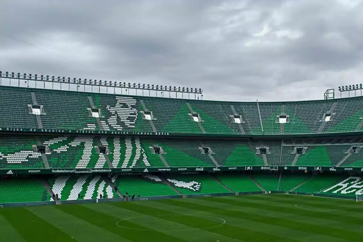 Estadio de fútbol con gradas verdes y blancas formando una imagen, bajo un cielo nublado. Estadio de fútbol con gradas verdes y blancas formando una imagen, bajo un cielo nublado.