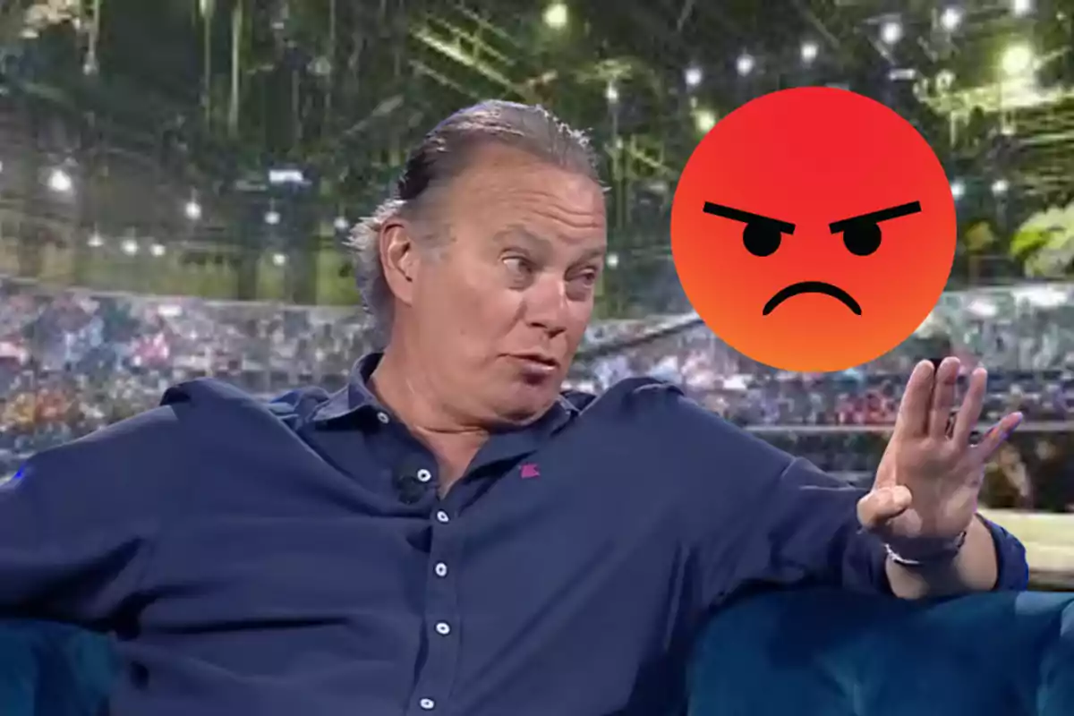 Un home amb camisa blava està assegut en un sofà amb un gest de sorpresa mentre un emoji de cara enfadada flota a prop d'ell en un fons de llums brillants.