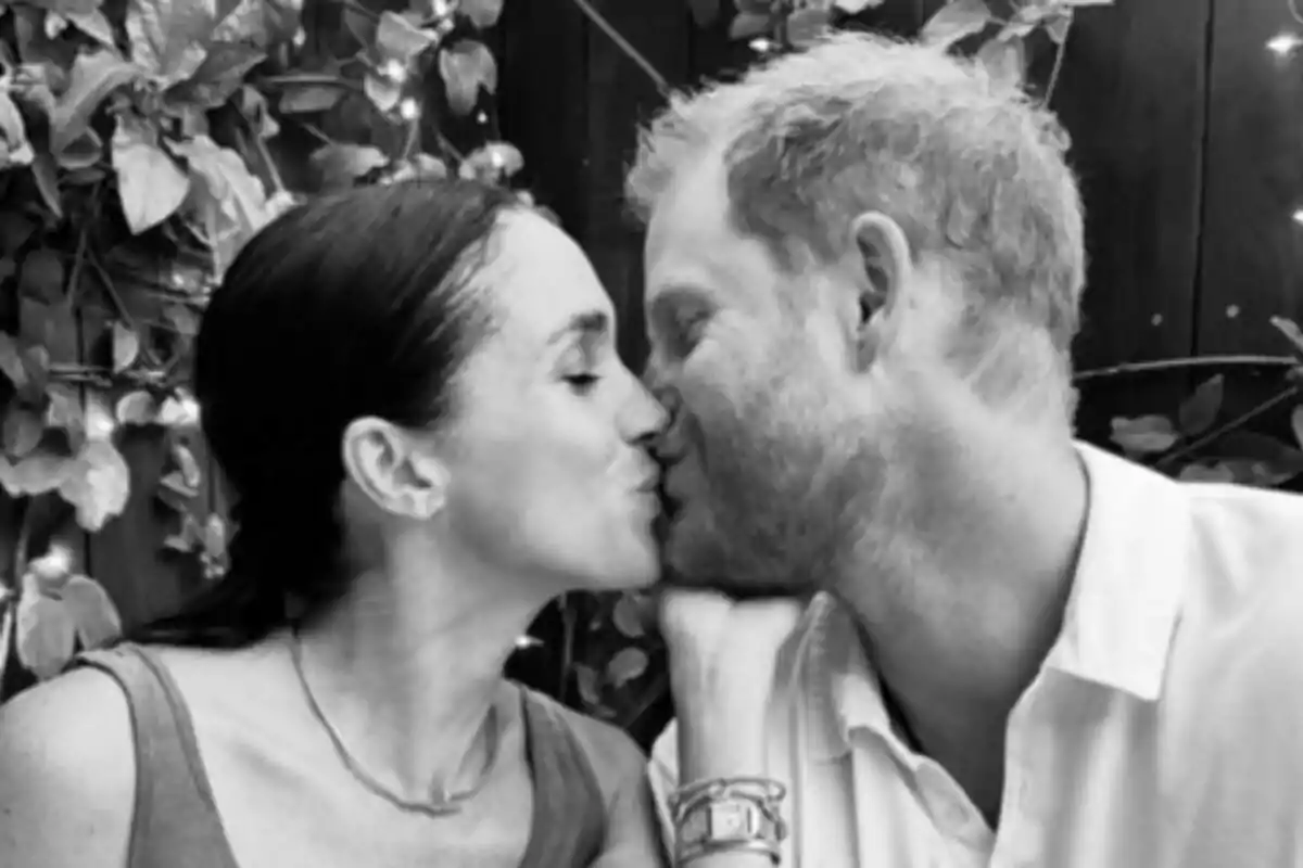 A couple—Meghan Markle and Prince Harry—kiss in a setting with plants and lights. A couple—Meghan Markle and Prince Harry—kiss in a setting with plants and lights.