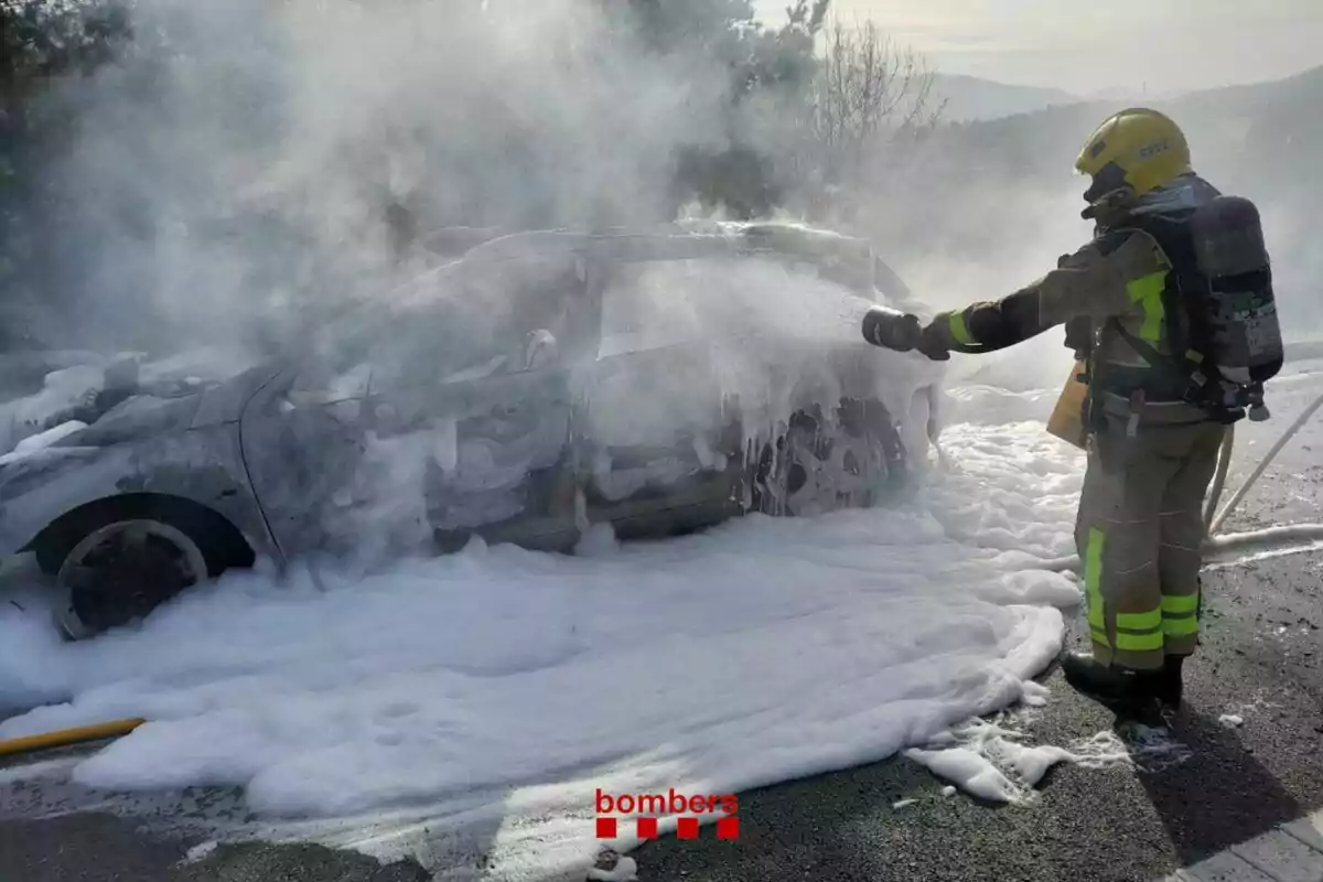 Un bombero apaga un incendio en un coche cubierto de espuma.