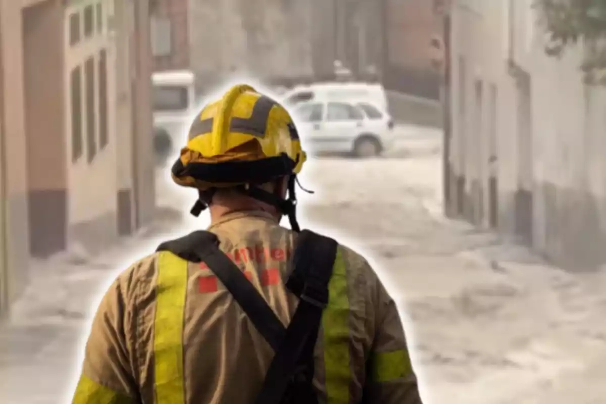 Un bombero de espaldas observa una calle inundada.