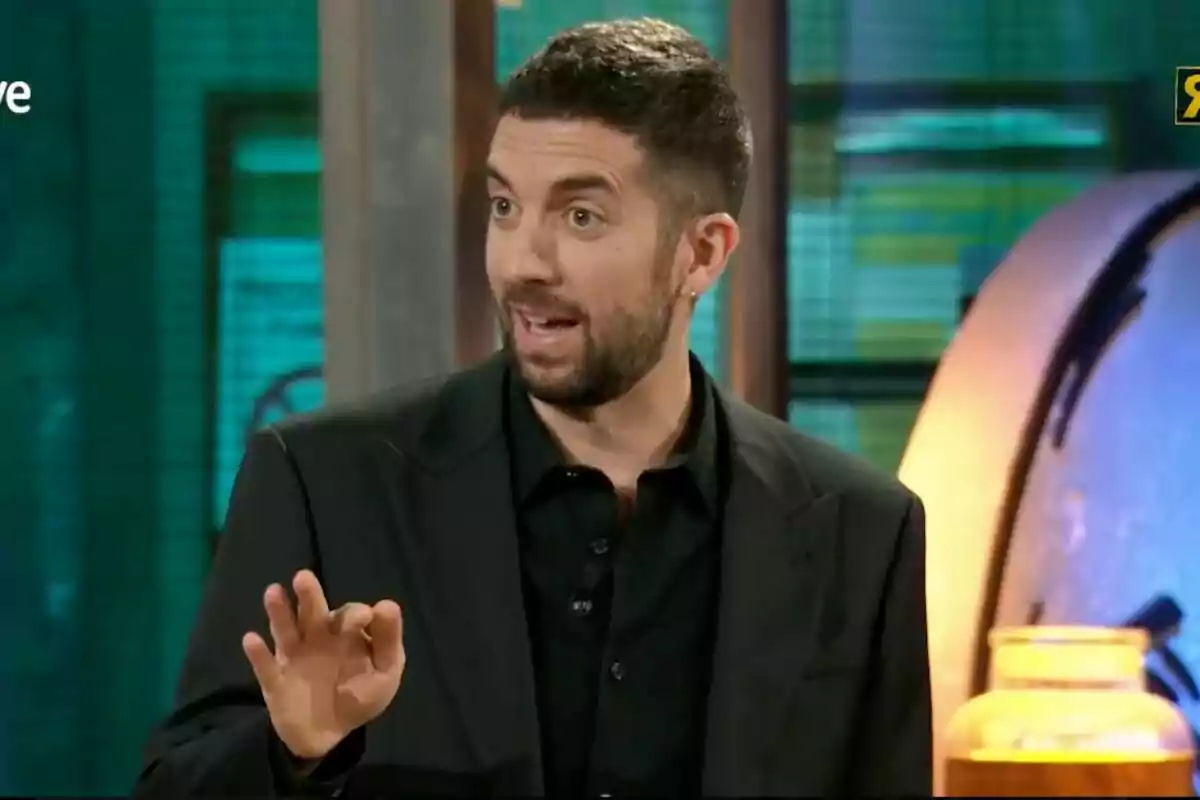 David Broncano amb barba i cabell curt està parlant i gesticulant amb la mà en un entorn il·luminat a 'La Revuelta'. David Broncano amb barba i cabell curt està parlant i gesticulant amb la mà en un entorn il·luminat a 'La Revuelta'.