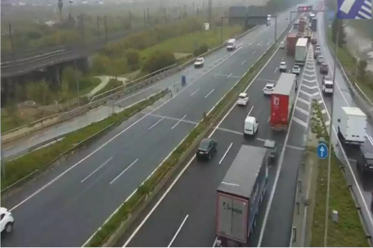 Una autopista amb trànsit moderat i diversos camions i cotxes circulant en un dia ennuvolat.