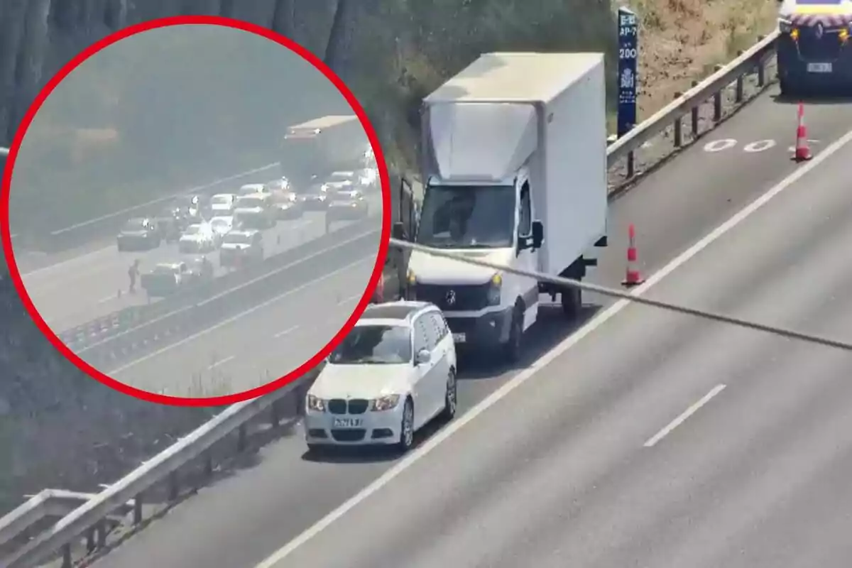 Un camió i un cotxe blanc estan aturats al voral d’una autopista al costat de cons taronges mentre al fons s’observa un embús de trànsit ressaltat amb un cercle vermell.