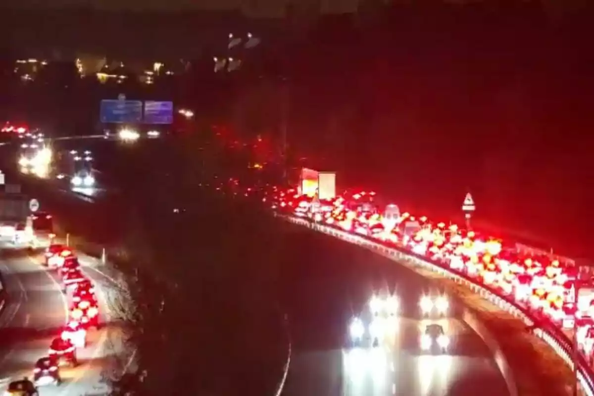 Una carretera congestionada por el tráfico nocturno con largas filas de luces traseras rojas de los vehículos.