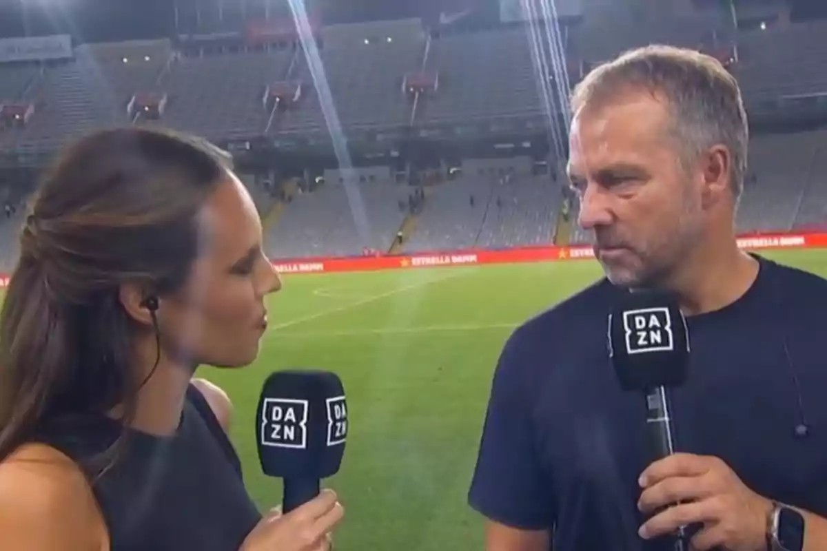 Dues persones estan sent entrevistades en un estadi de futbol, totes dues sostenint micròfons amb el logo de DAZN.