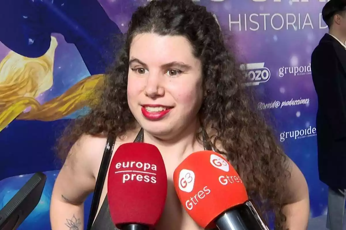 Carla Vigo somrient amb els llavis vermells davant de dos micròfons vermell i taronja Carla Vigo somrient amb els llavis vermells davant de dos micròfons vermell i taronja