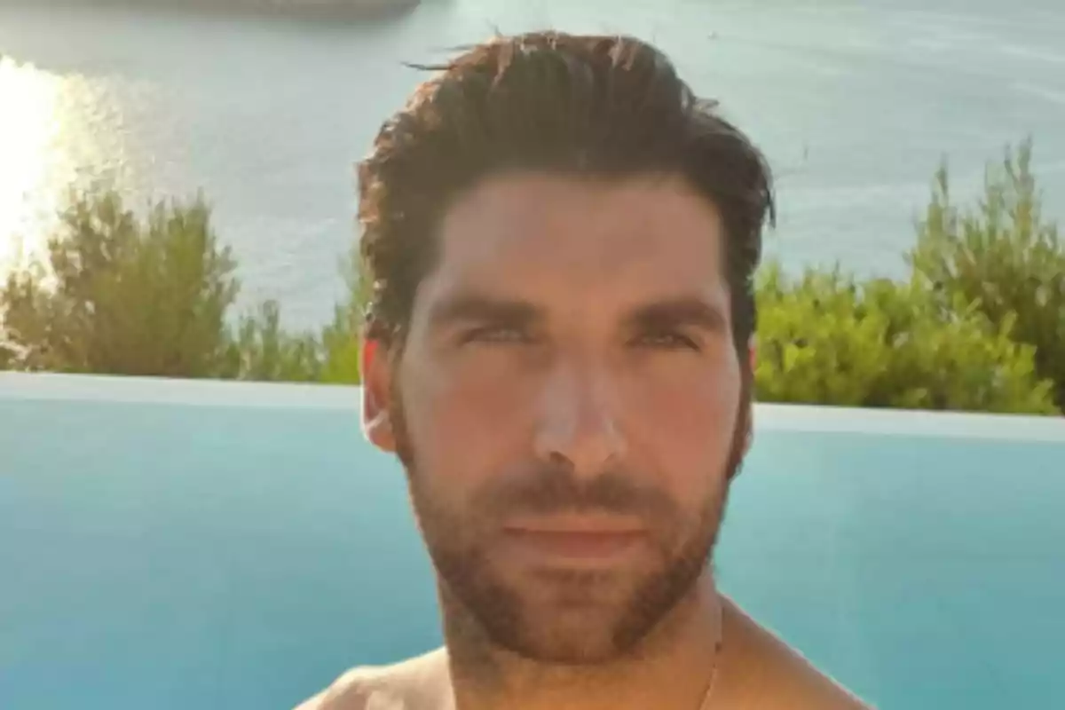 Un hombre frente a una piscina con un paisaje de árboles y agua al fondo. Un hombre frente a una piscina con un paisaje de árboles y agua al fondo.