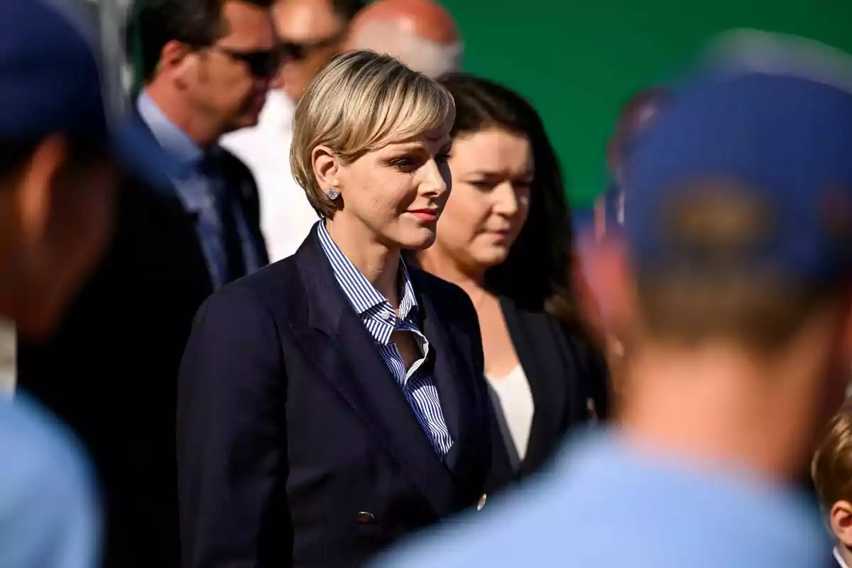 Charlene sonriendo en traje azul rodeada de otras personas Charlene sonriendo en traje azul rodeada de otras personas