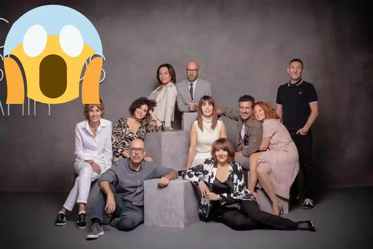 Un grup de persones posant juntes en un estudi fotogràfic amb un emoji de sorpresa superposat a la cantonada superior esquerra.