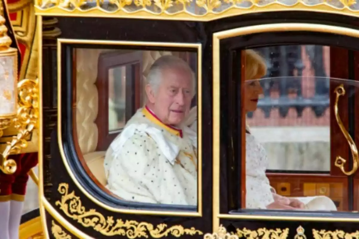 King Charles III and Queen Camilla, elegantly dressed, ride in a carriage decorated with golden details during his coronation day as King of England. King Charles III and Queen Camilla, elegantly dressed, ride in a carriage decorated with golden details during his coronation day as King of England.
