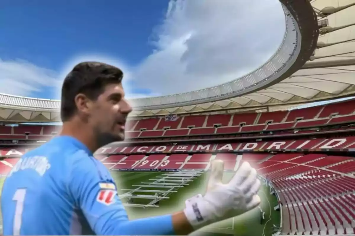 Un portero de fútbol con uniforme azul claro gesticulando en un estadio vacío con asientos rojos y un cielo parcialmente nublado.