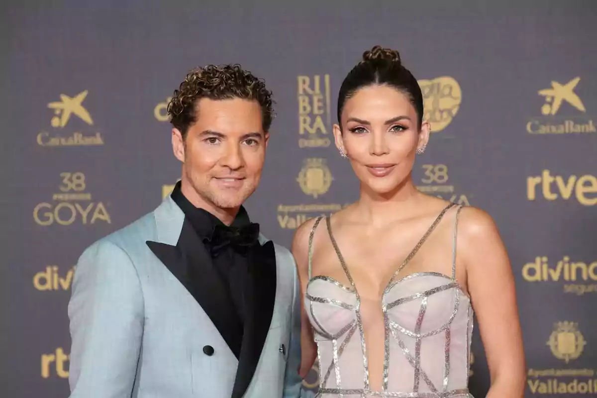 David Bisbal y Rosanna Zanetti posa elegantemente en la alfombra roja de un evento, con un fondo que muestra varios logotipos de patrocinadores y el nombre del evento. David Bisbal y Rosanna Zanetti posa elegantemente en la alfombra roja de un evento, con un fondo que muestra varios logotipos de patrocinadores y el nombre del evento.