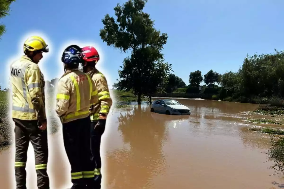 Bombers observant un cotxe atrapat en una inundació a una àrea rural.