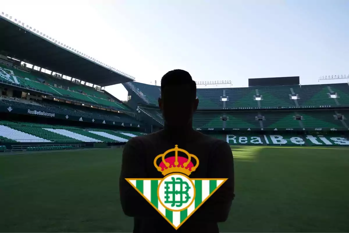 Persona amb la silueta fosca i el logotip del Real Betis Balompié en un estadi de futbol buit.