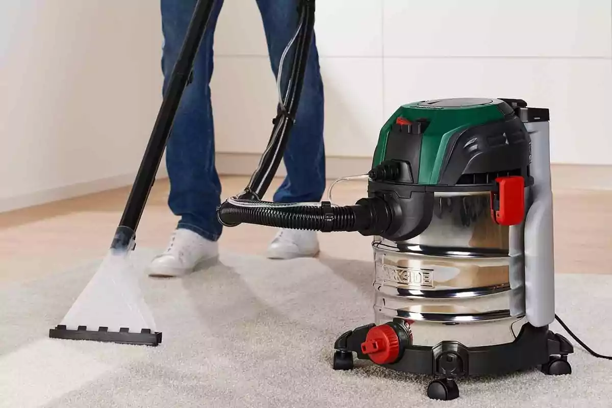 A person using an industrial vacuum cleaner to clean carpets.