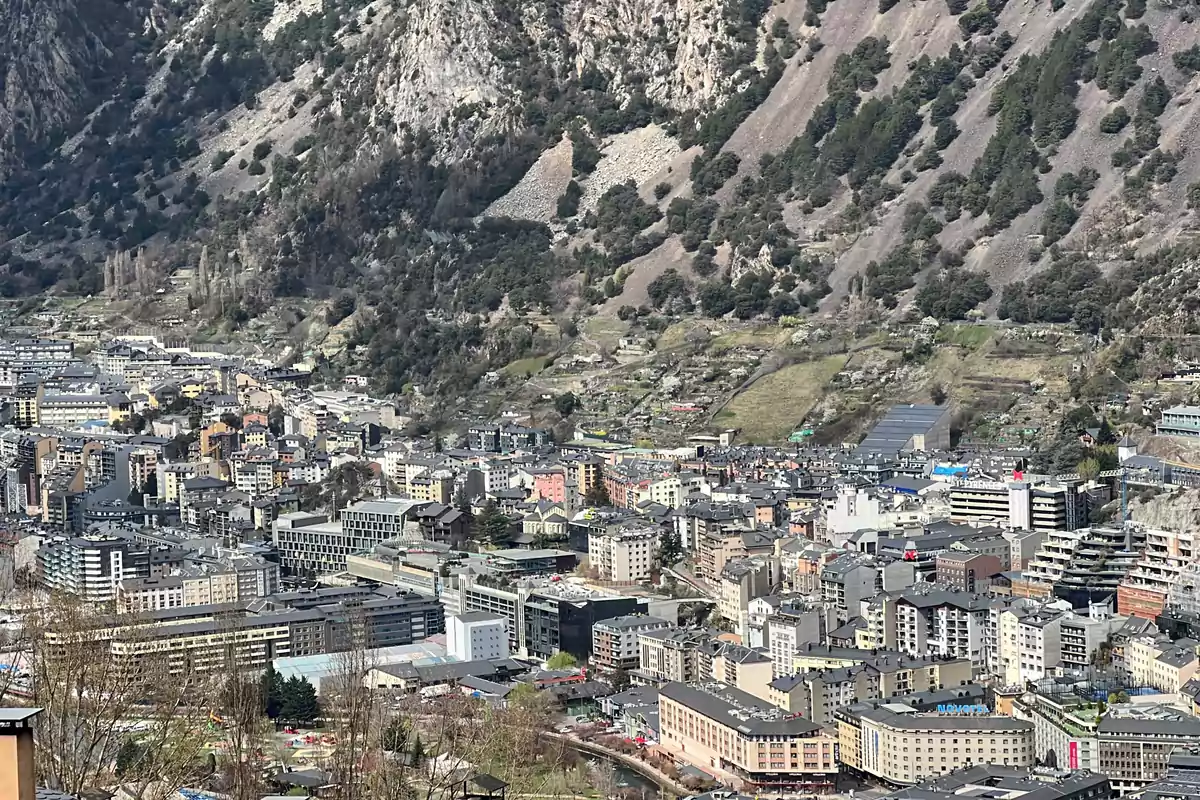 Vista panorámica de una ciudad rodeada de montañas con edificios y vegetación.